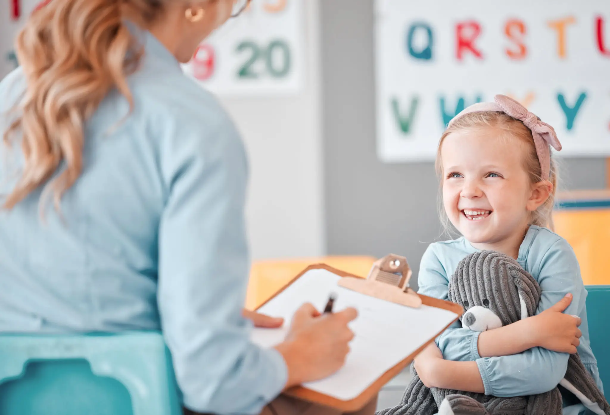 Smiling girl hugging stuffed animal during assessment