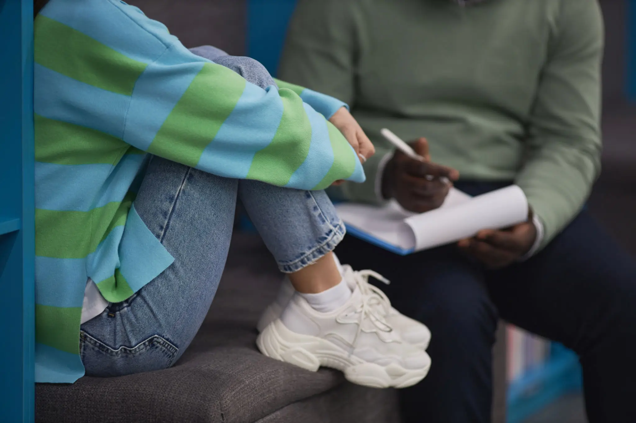 Person in striped sweater sitting, person taking notes