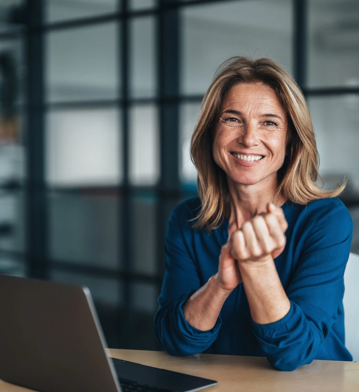 Smiling woman sitting at desk with laptop.